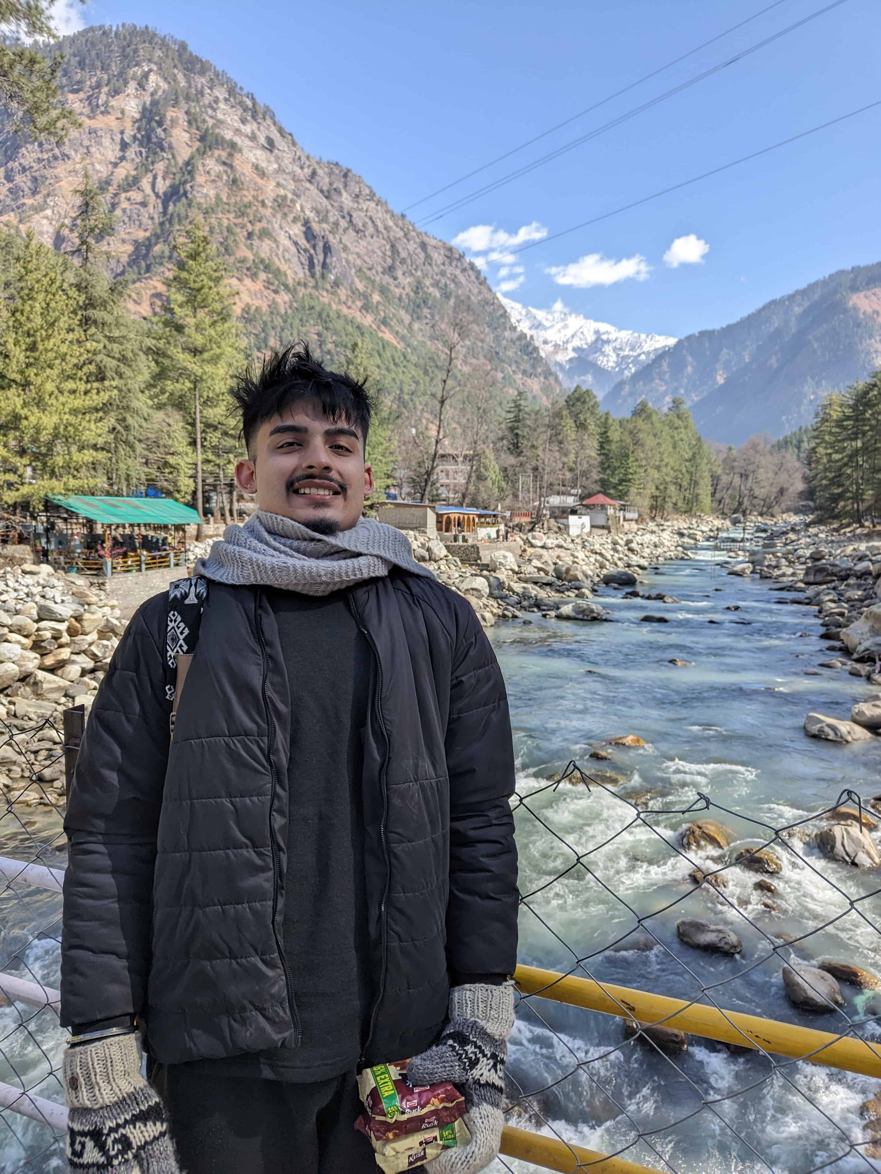 A person standing in front of Parvati river in Kasol, Himachal Pradesh, India.